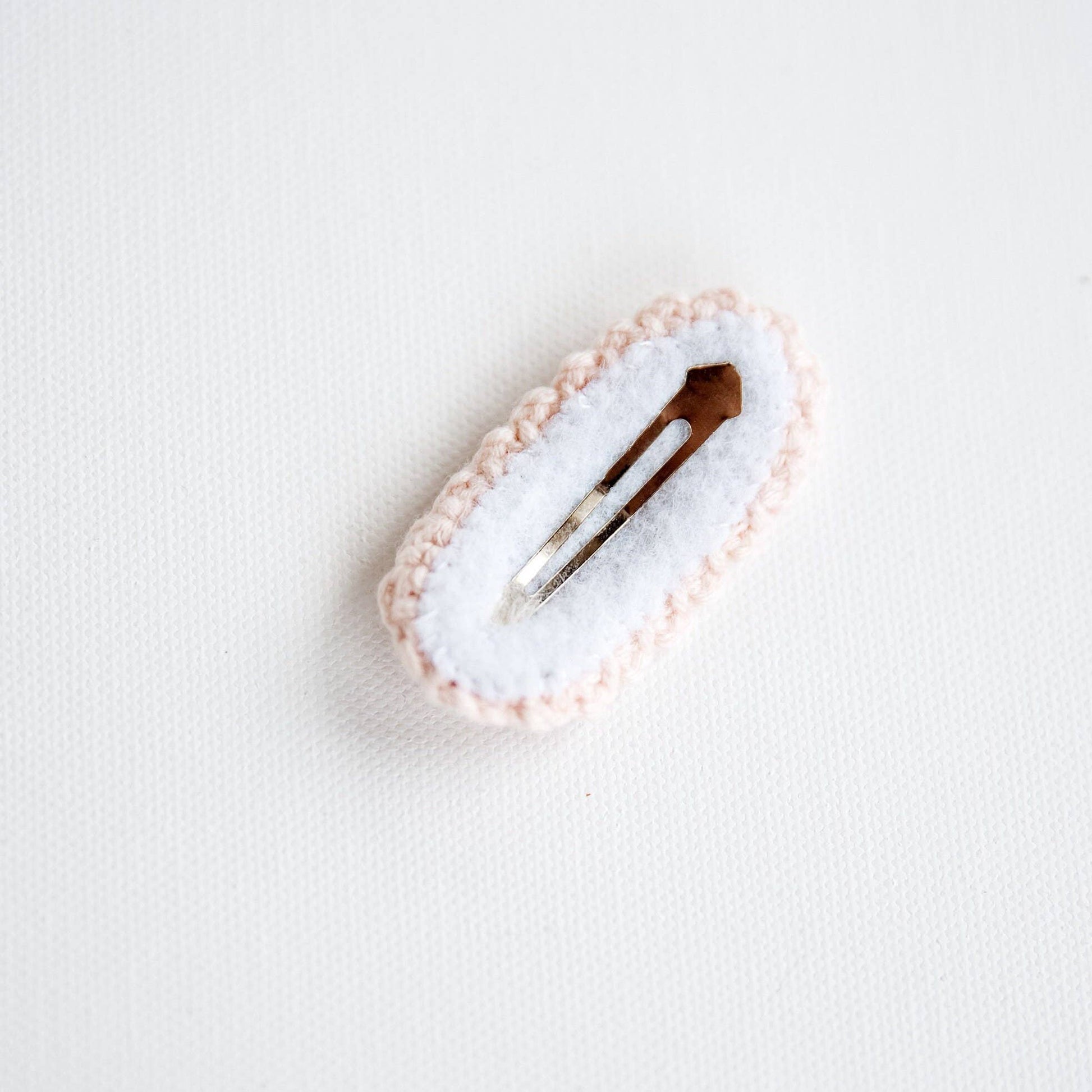 Hair clip with a white cushion and pink border on a light gray background