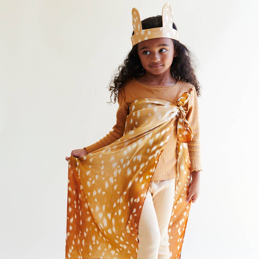 Child in a deer costume with a headband and scarf on a white background