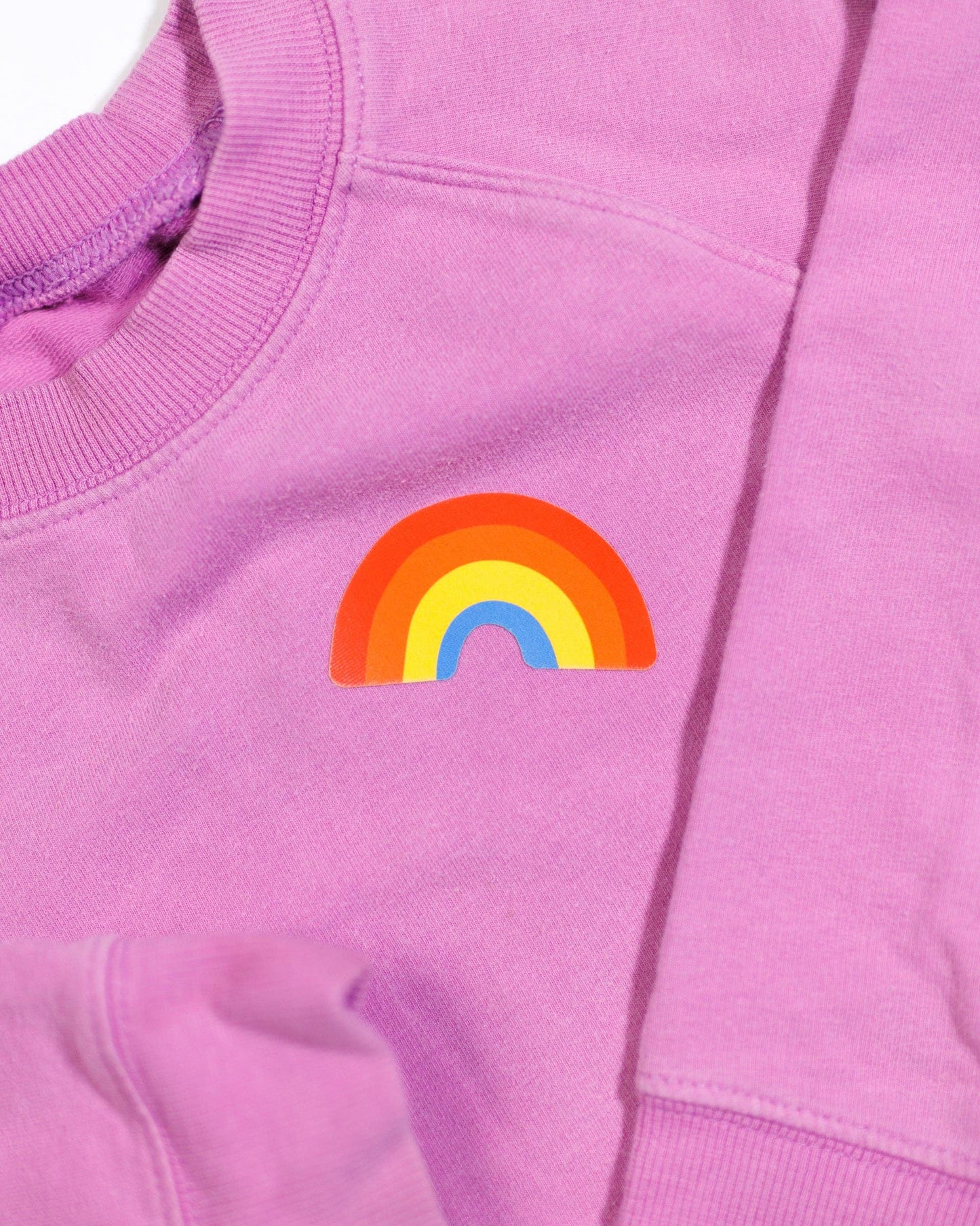 Pink sweatshirt with a rainbow design on a plain background
