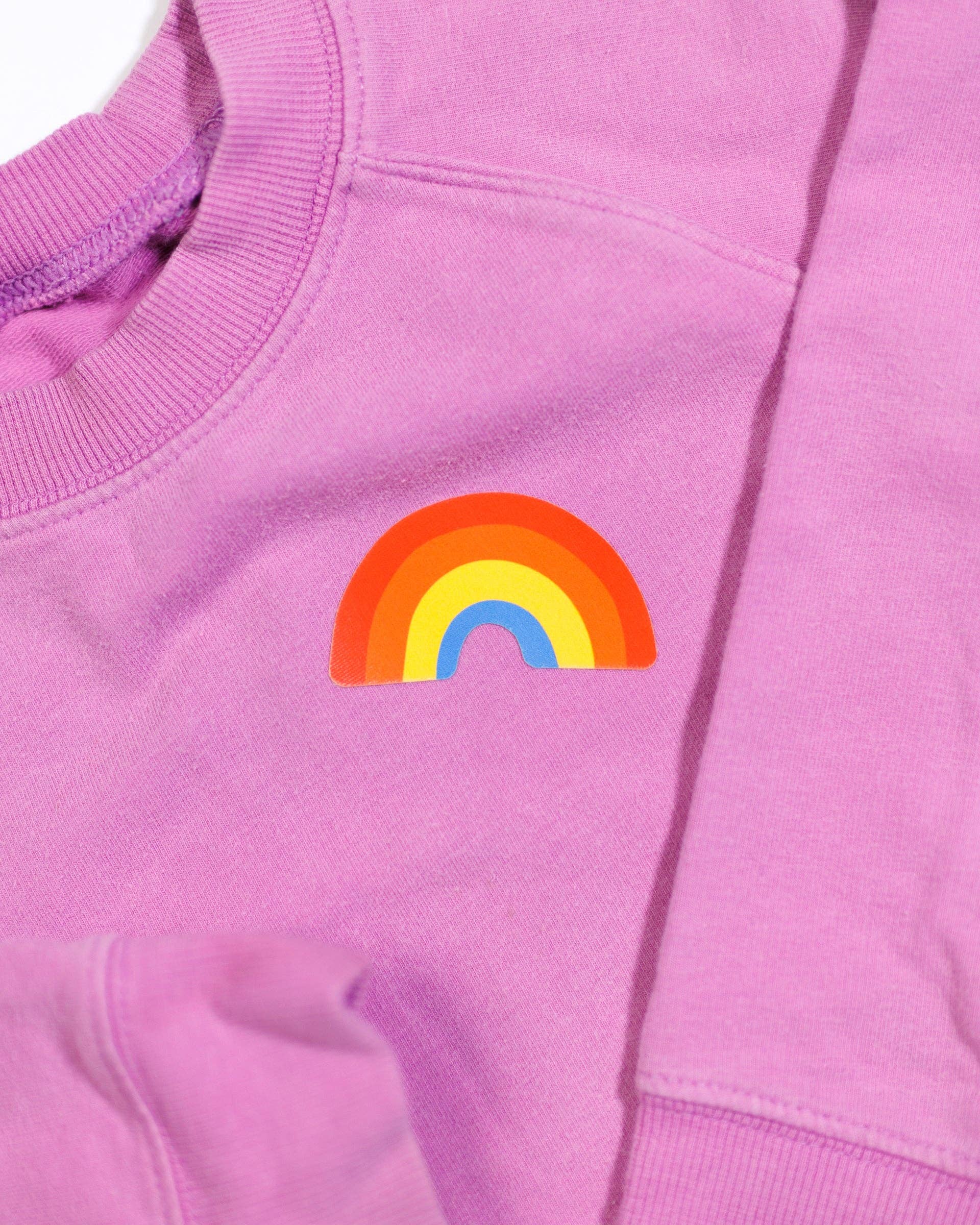 Pink sweatshirt with a rainbow design on a plain background