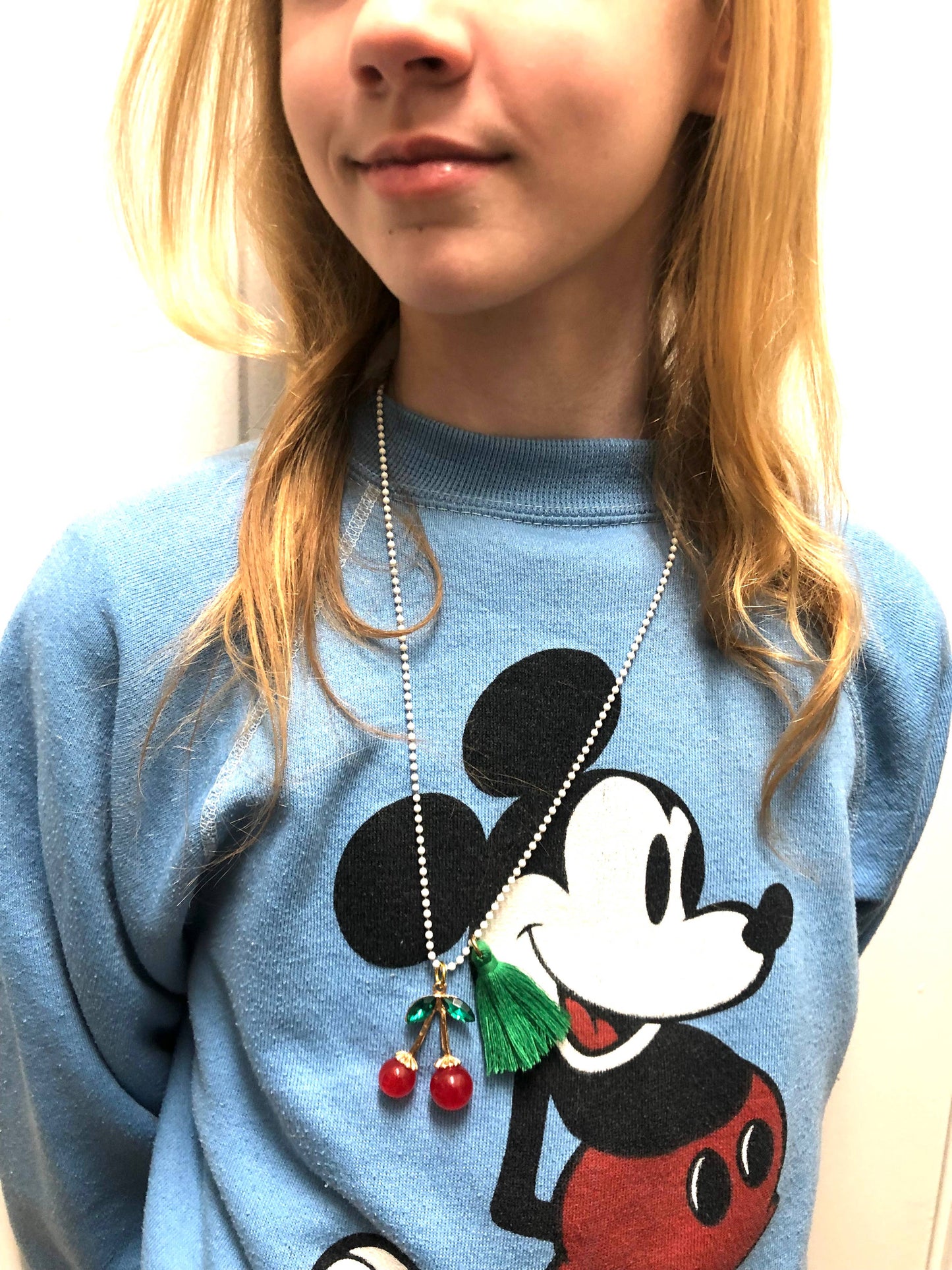 Person wearing a blue sweatshirt with a cartoon character design and a necklace.