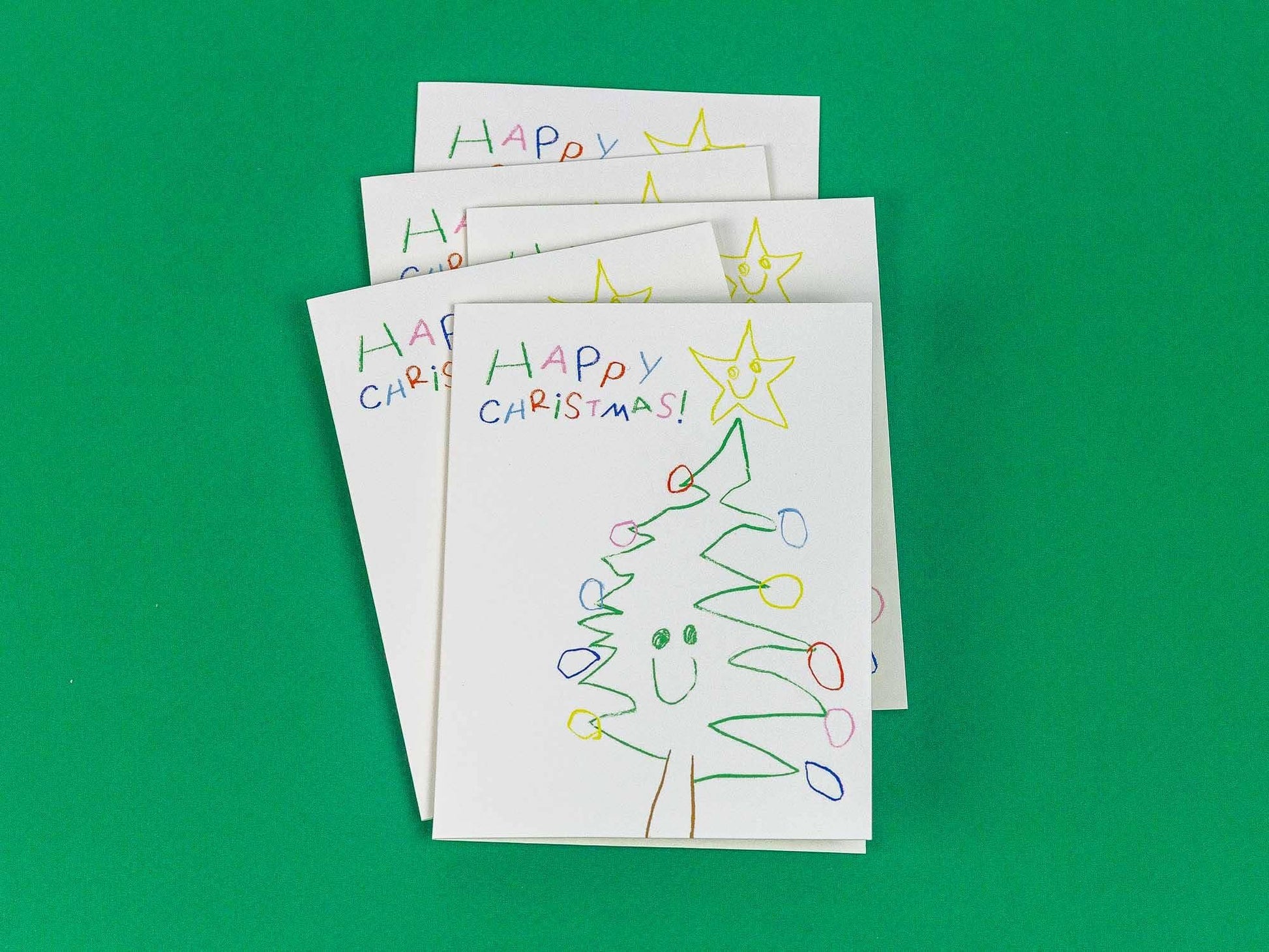 Stack of hand-drawn Christmas cards with a tree and 'Happy Christmas!' text on a green background