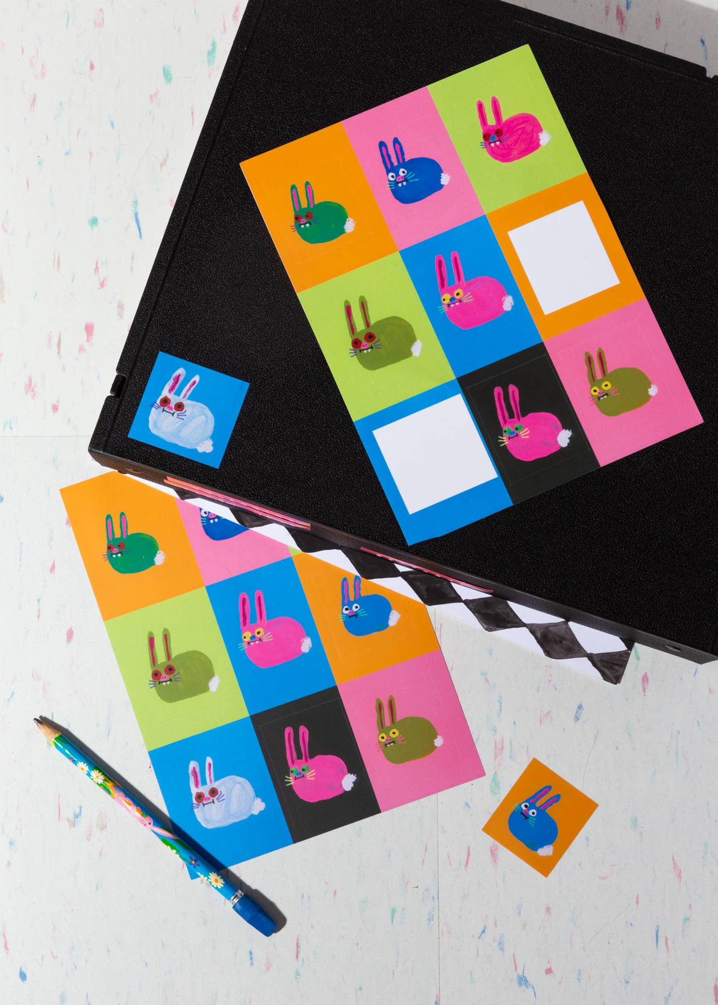 Colorful rabbit-themed stickers on a black surface with a pencil and additional stickers in the foreground.
