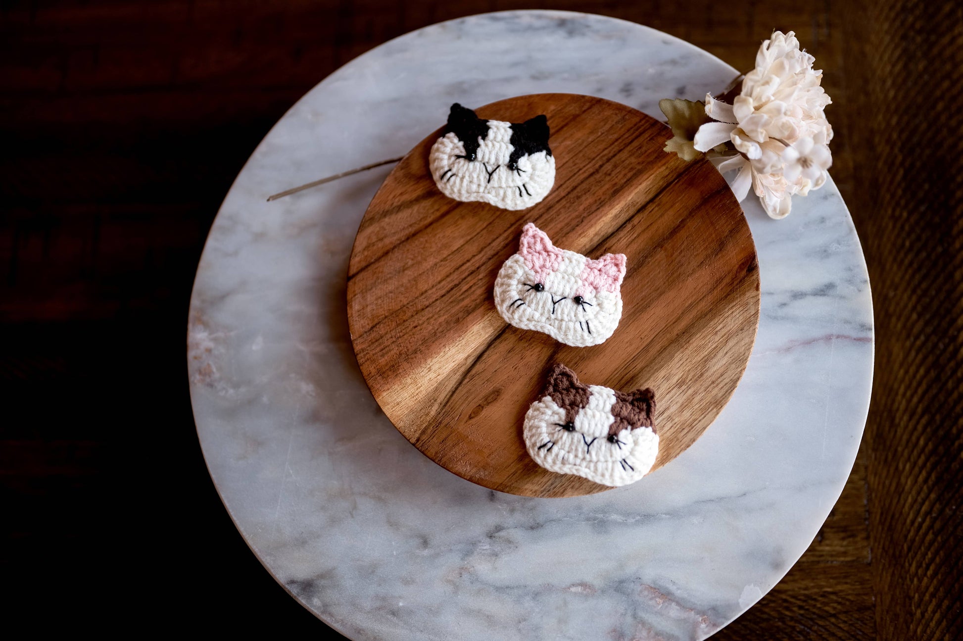 Three cat-shaped hair clips a wooden board with a marble base