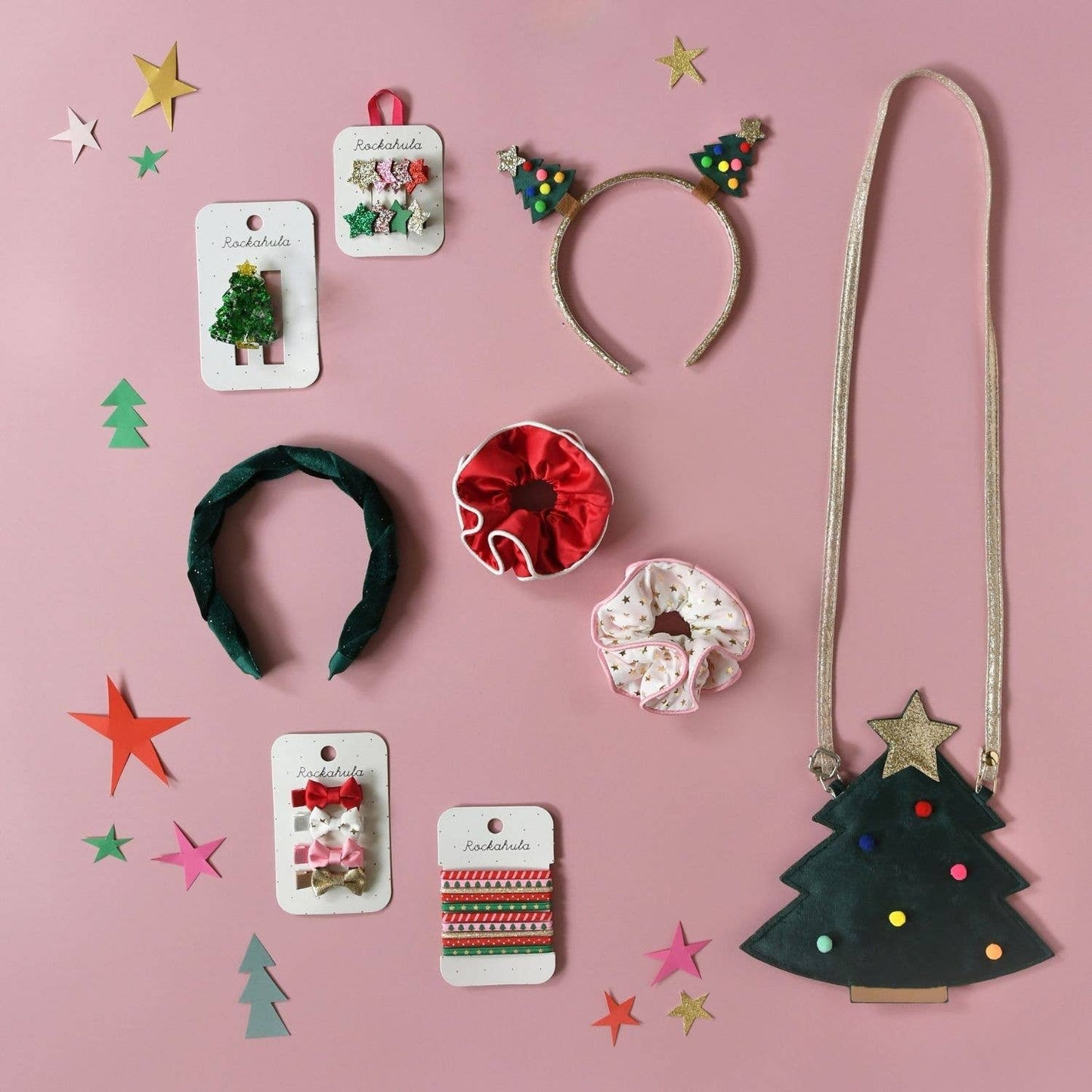 Collection of Christmas-themed hair accessories on a pink background with decorative elements.
