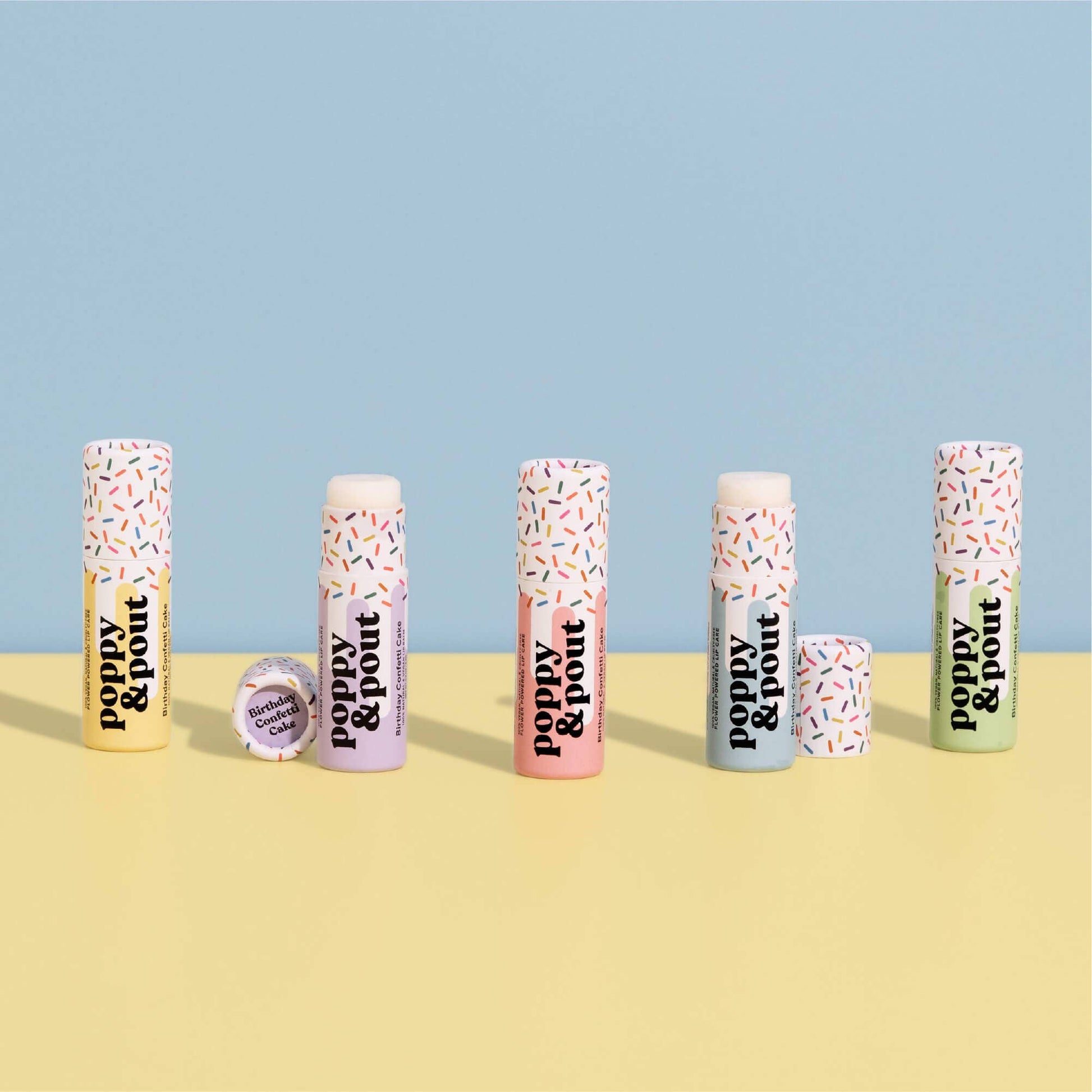 Set of lip balm tubes with 'Poppy & Pout' branding on a yellow and blue background