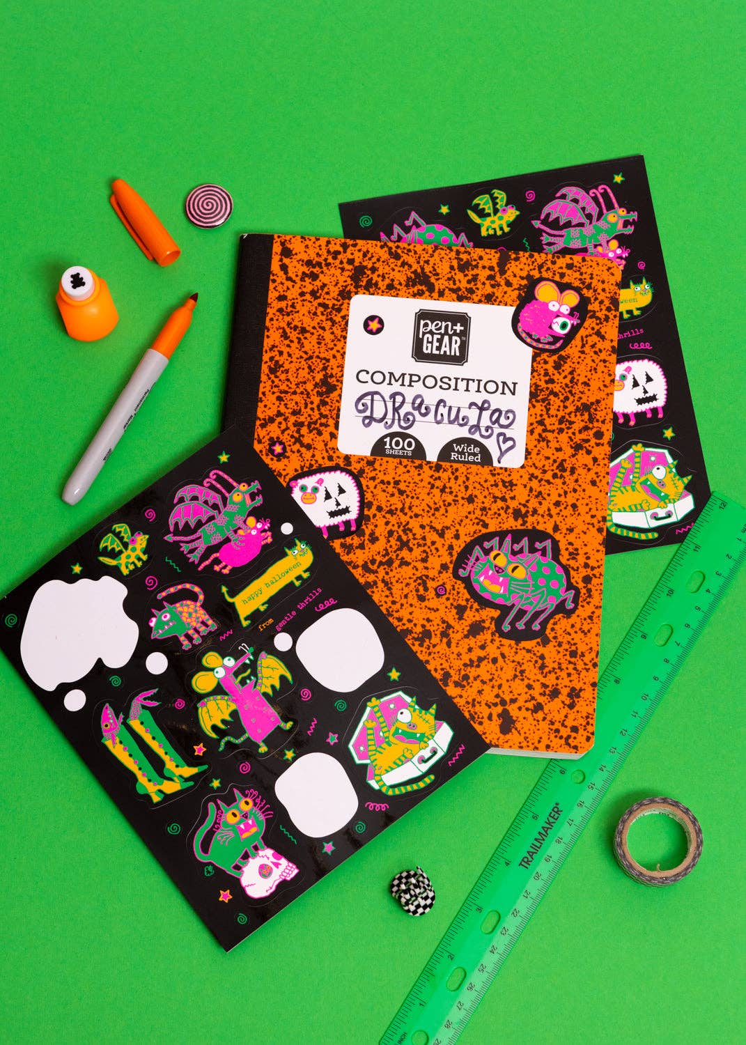 A styled flat-lay of two 'Don't Fear the Dark' Composition B 'Night Crawler' notebooks on a bright green background, surrounded by craft and playdough props.
