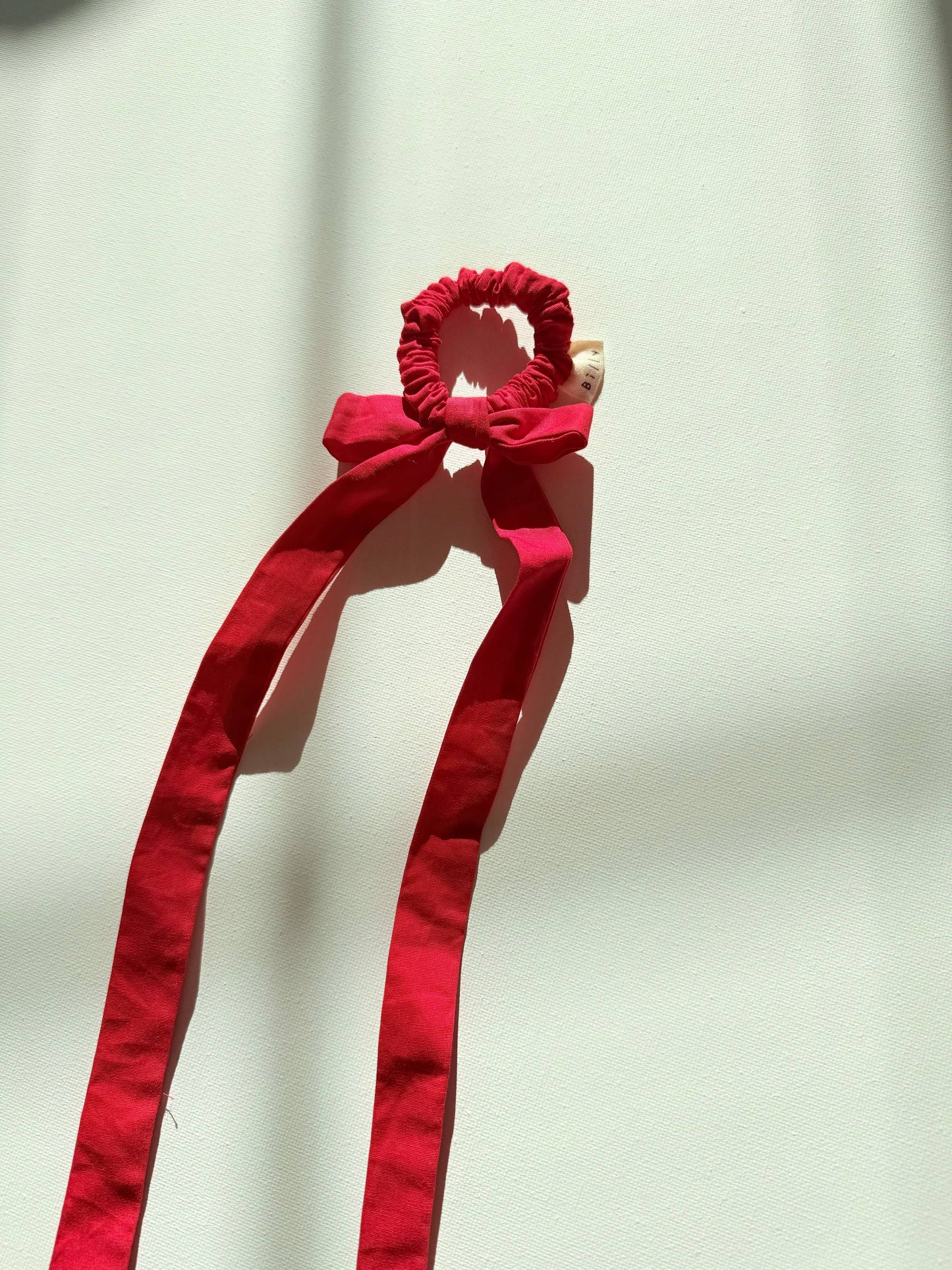 Red hair scrunchie with a bow on a white background
