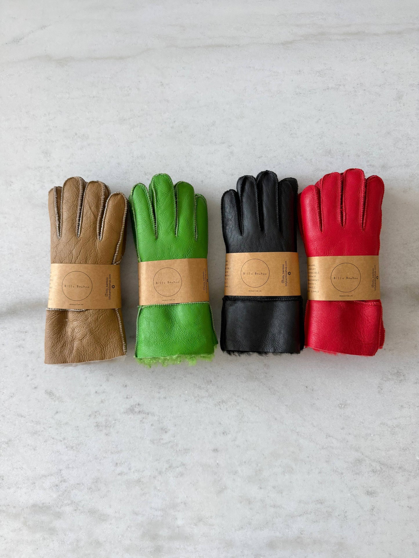 Four pairs of leather gloves in brown, green, black, and red on a light gray background.