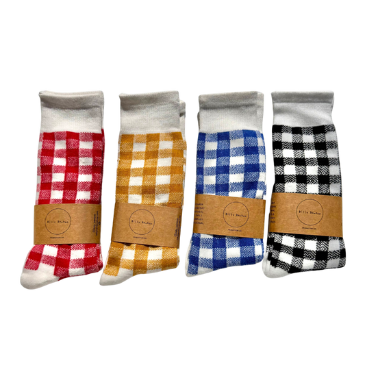 Four pairs of folded gingham socks in different colorways, packaged with brown paper bands. The colorways shown are red and white, mustard yellow and white, blue and white, and black and white.