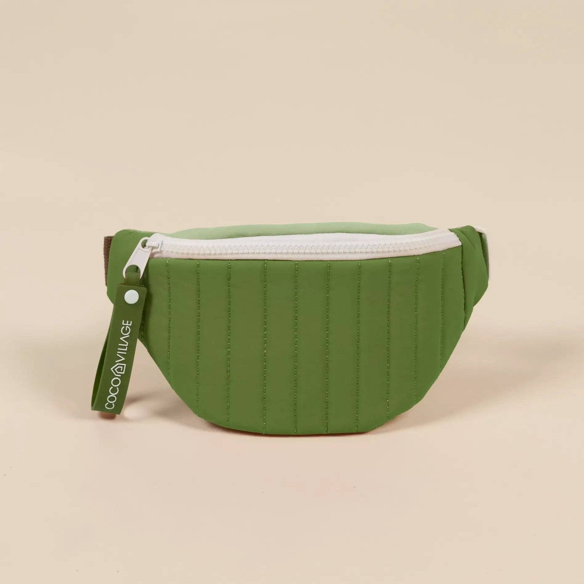 Green waist bag with a white zipper on a beige background