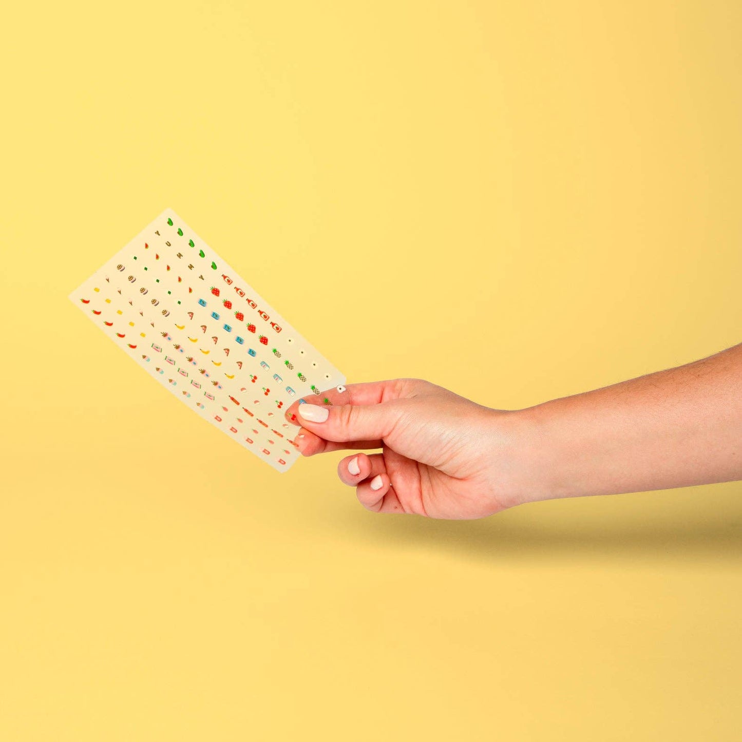 Hand holding a colorful patterned card against a yellow background