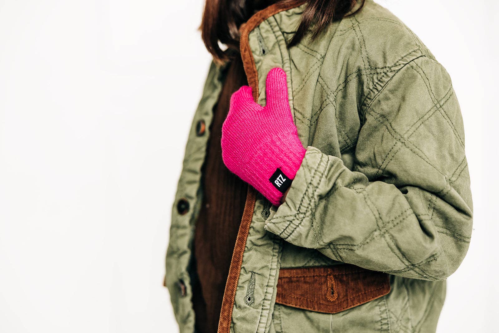 Person wearing a green jacket with a pink glove on a white background