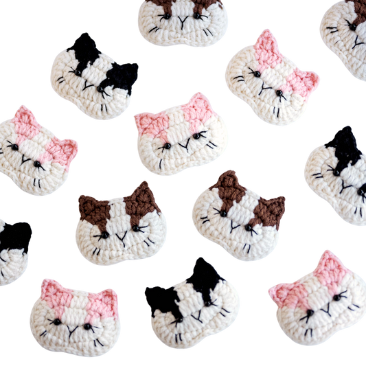 Pattern of crocheted cat face designs on a white background
