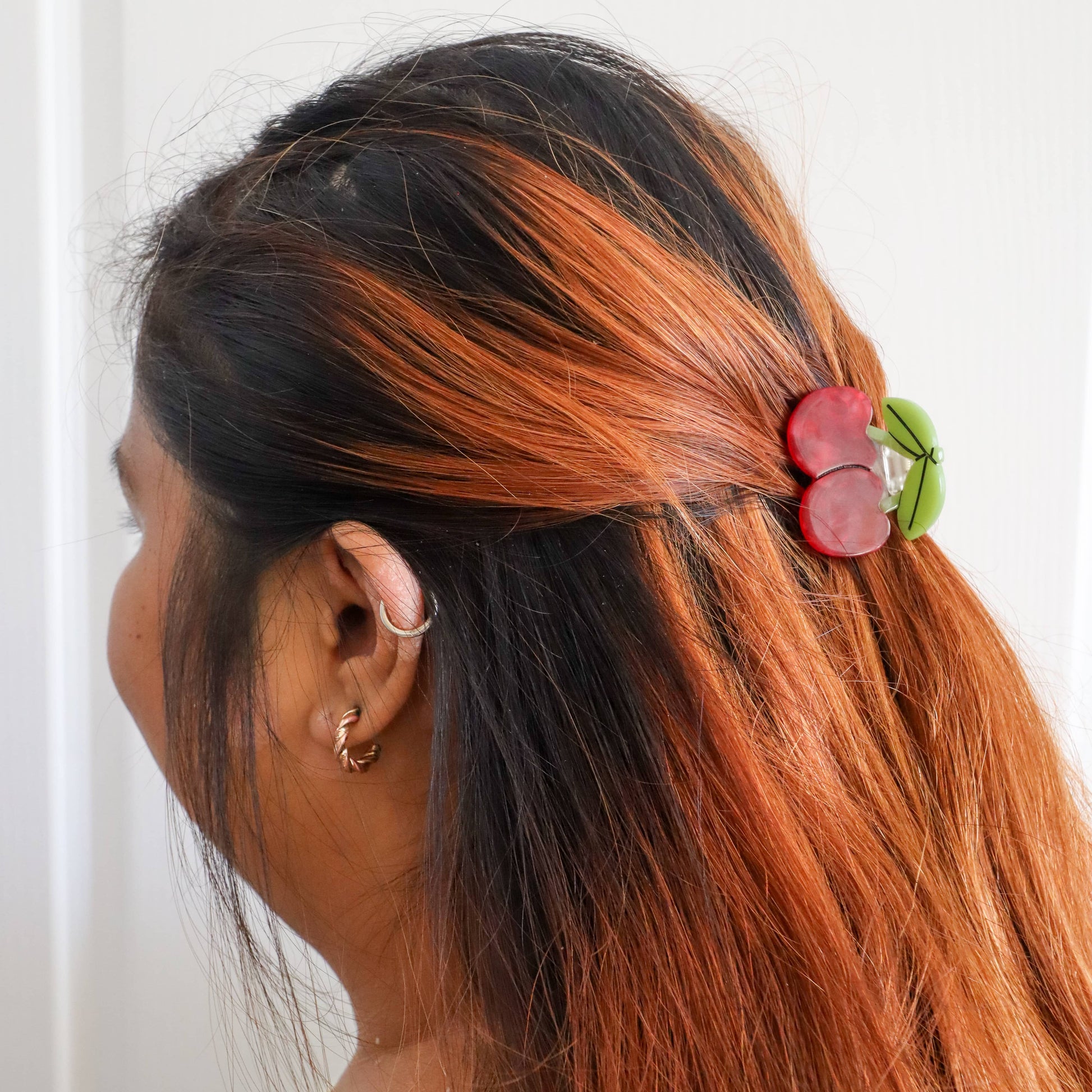Person with black and orange hair wearing a decorative hair clip against a white background