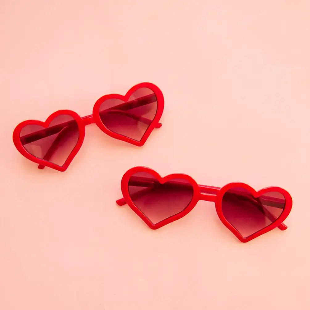 Red heart-shaped sunglasses on a pink background