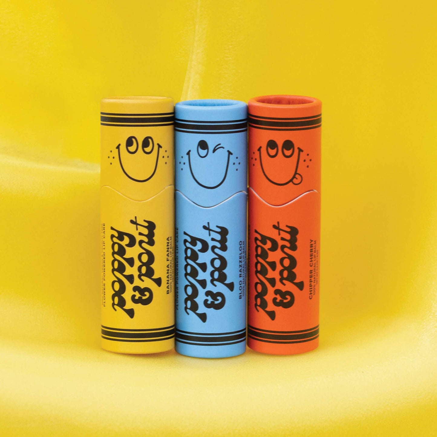 Three colorful tubes of lip balm on a yellow background