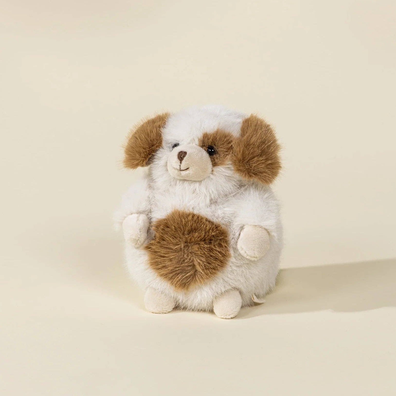 Stuffed dog toy with brown and white fur on a beige background