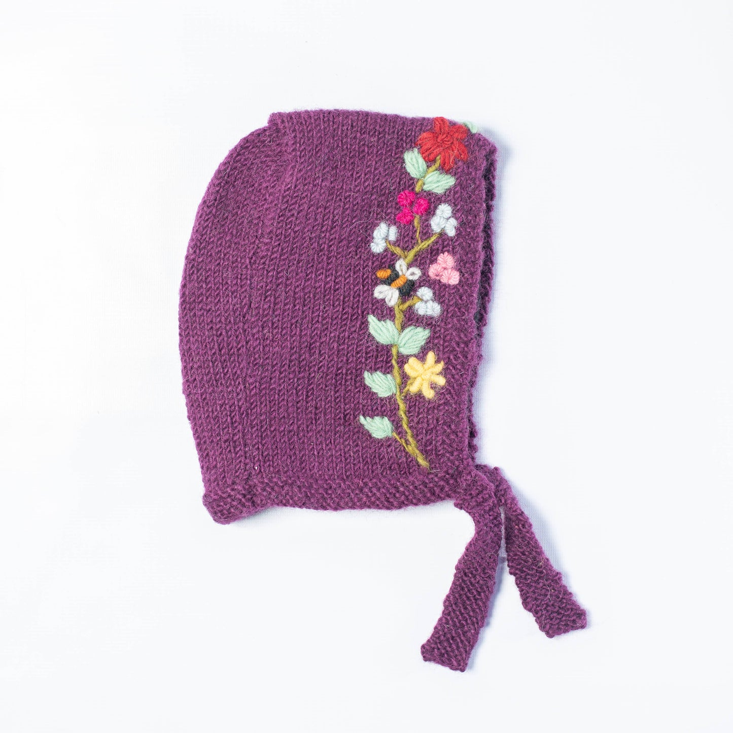 Knitted bonnet with floral embroidery on a white background