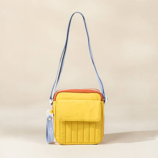 Yellow crossbody bag with a blue strap on a beige background