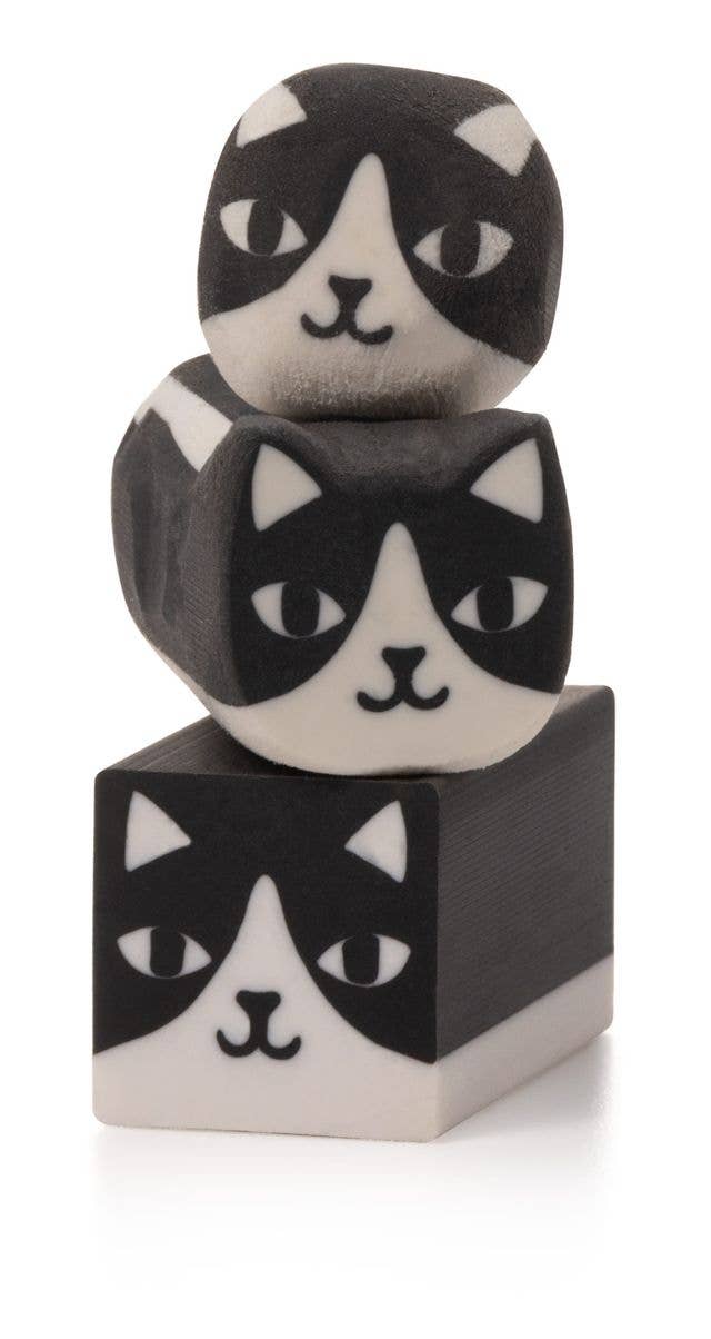 Three stacked wooden blocks with black and white cat face designs on a white background