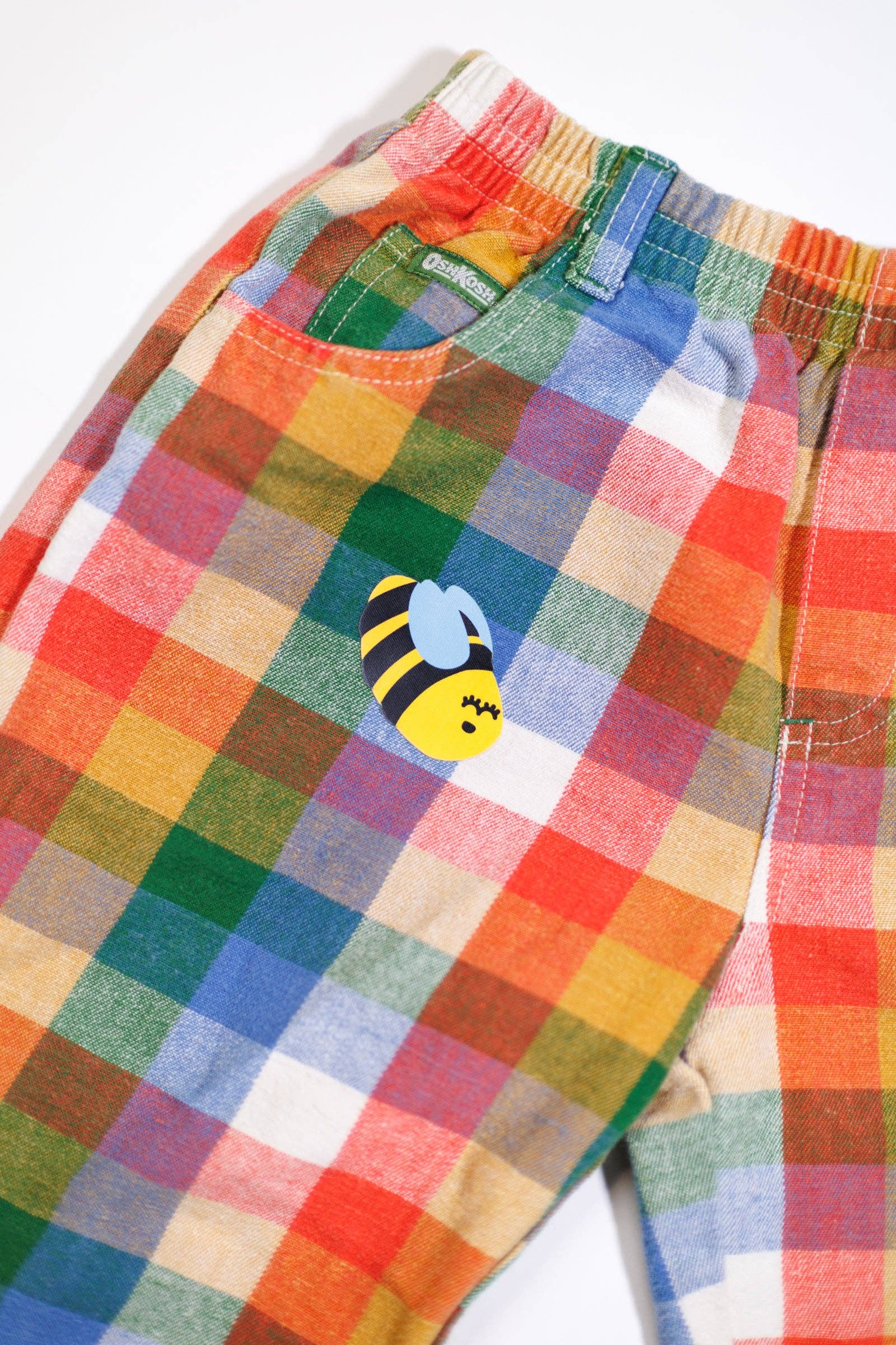Colorful checkered shorts with a bee design on a white background