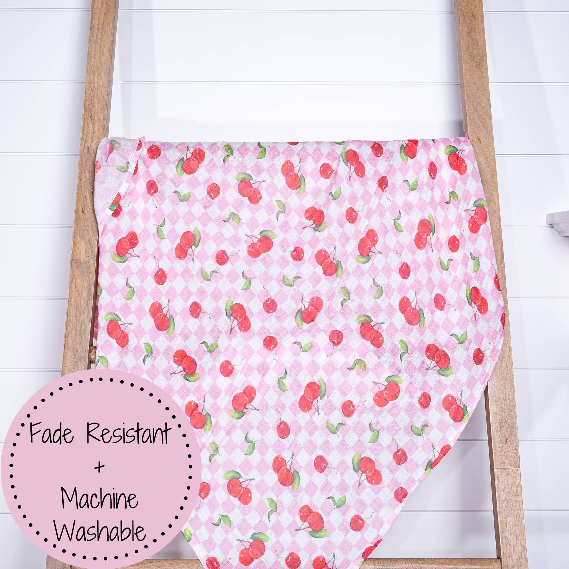 Pink fabric with cherry pattern on a wooden ladder against a white background