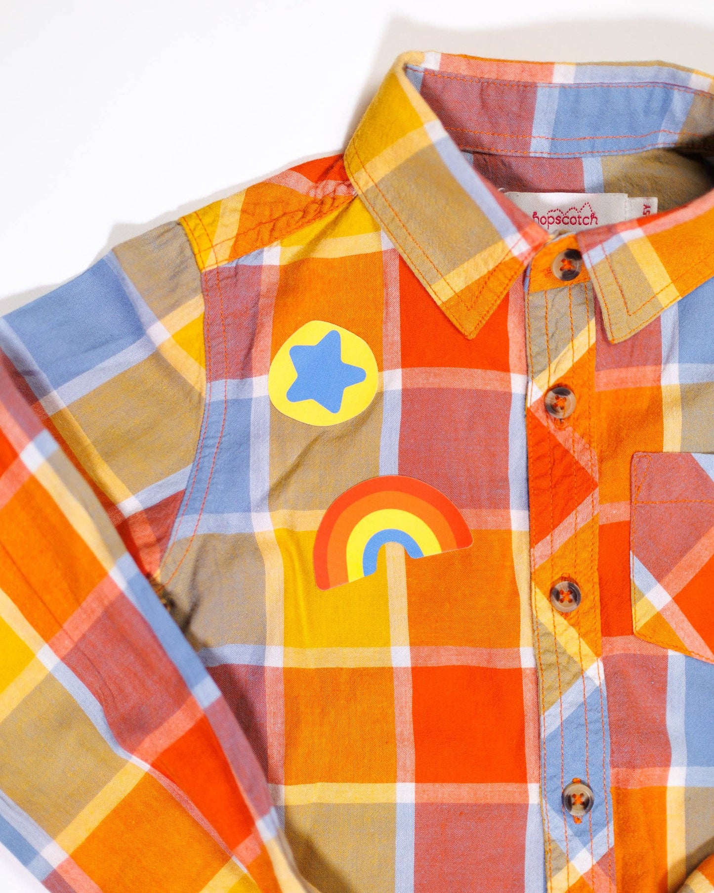 Colorful plaid shirt with rainbow and star design on a white background