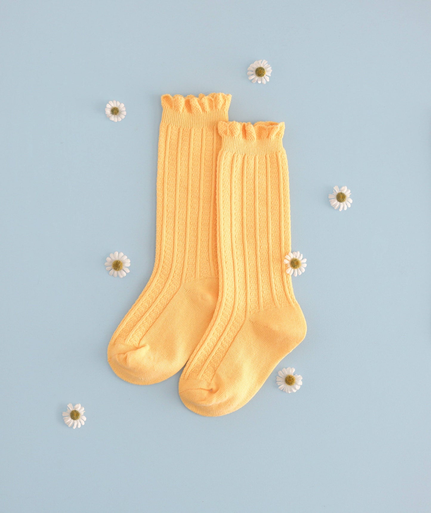 Pair of yellow socks on a light blue background with small white flowers.