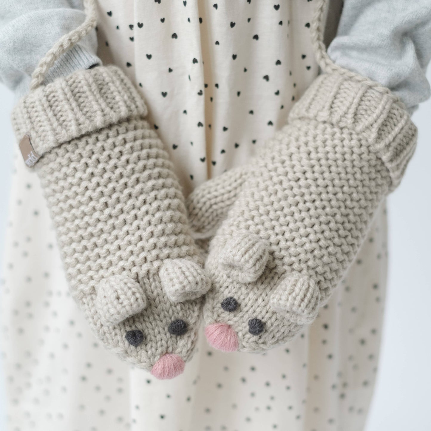 Pair of knitted mittens with mouse design on a white background