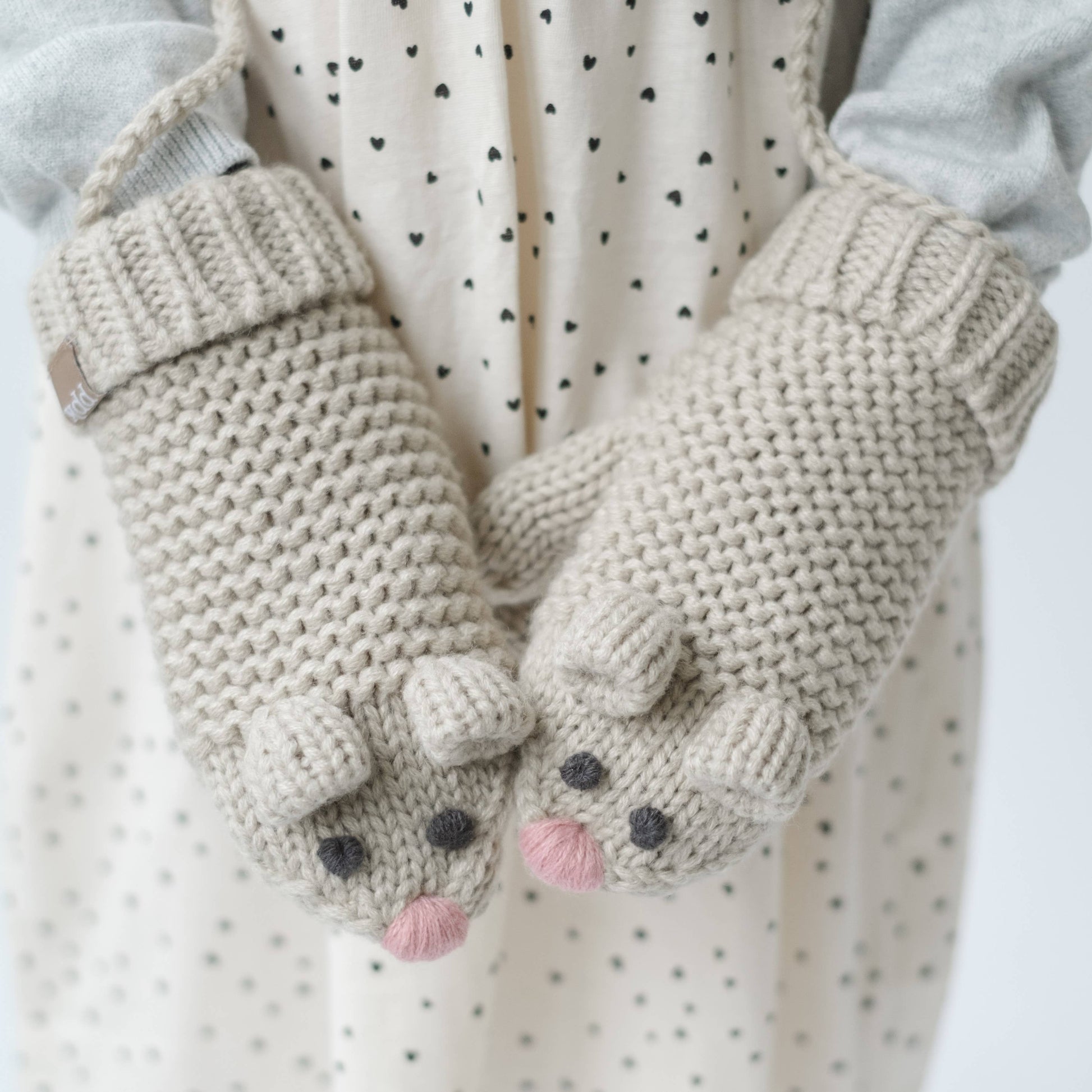Pair of knitted mittens with mouse design on a white background