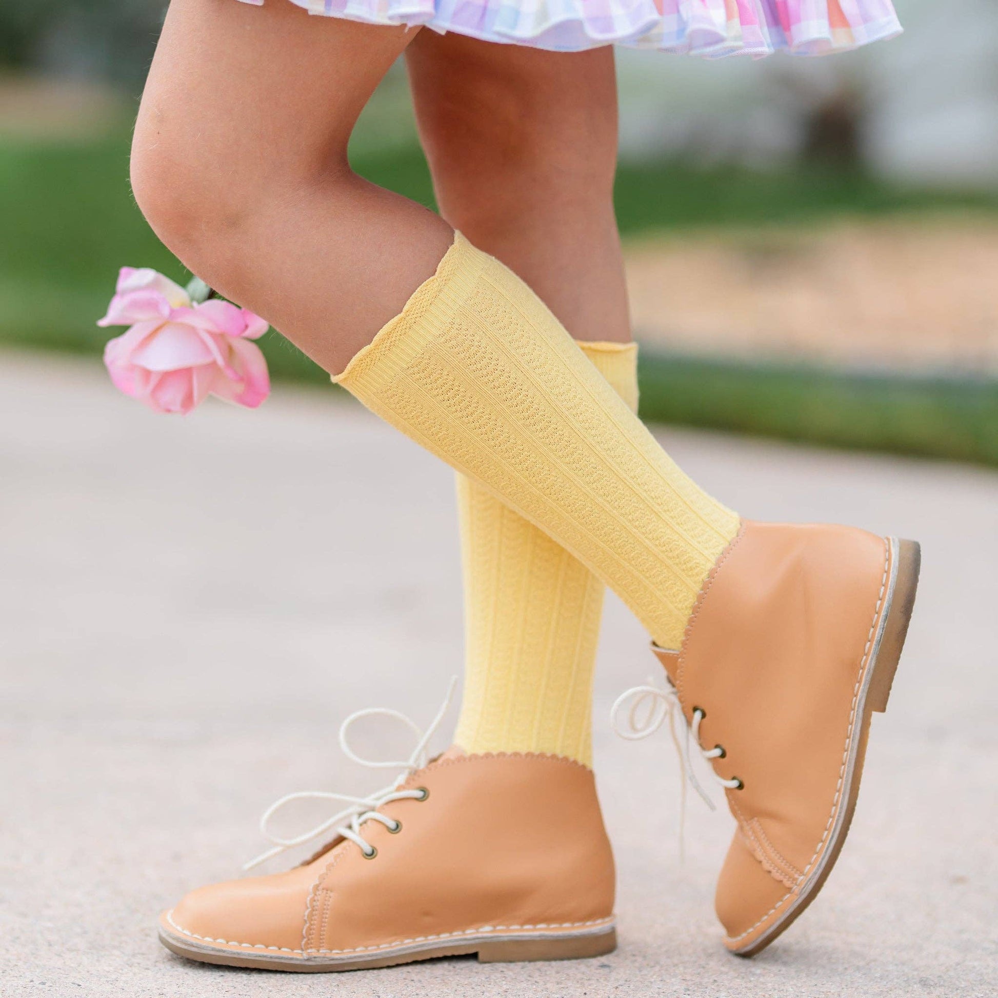Person wearing yellow knee-high socks and tan shoes with a blurred background