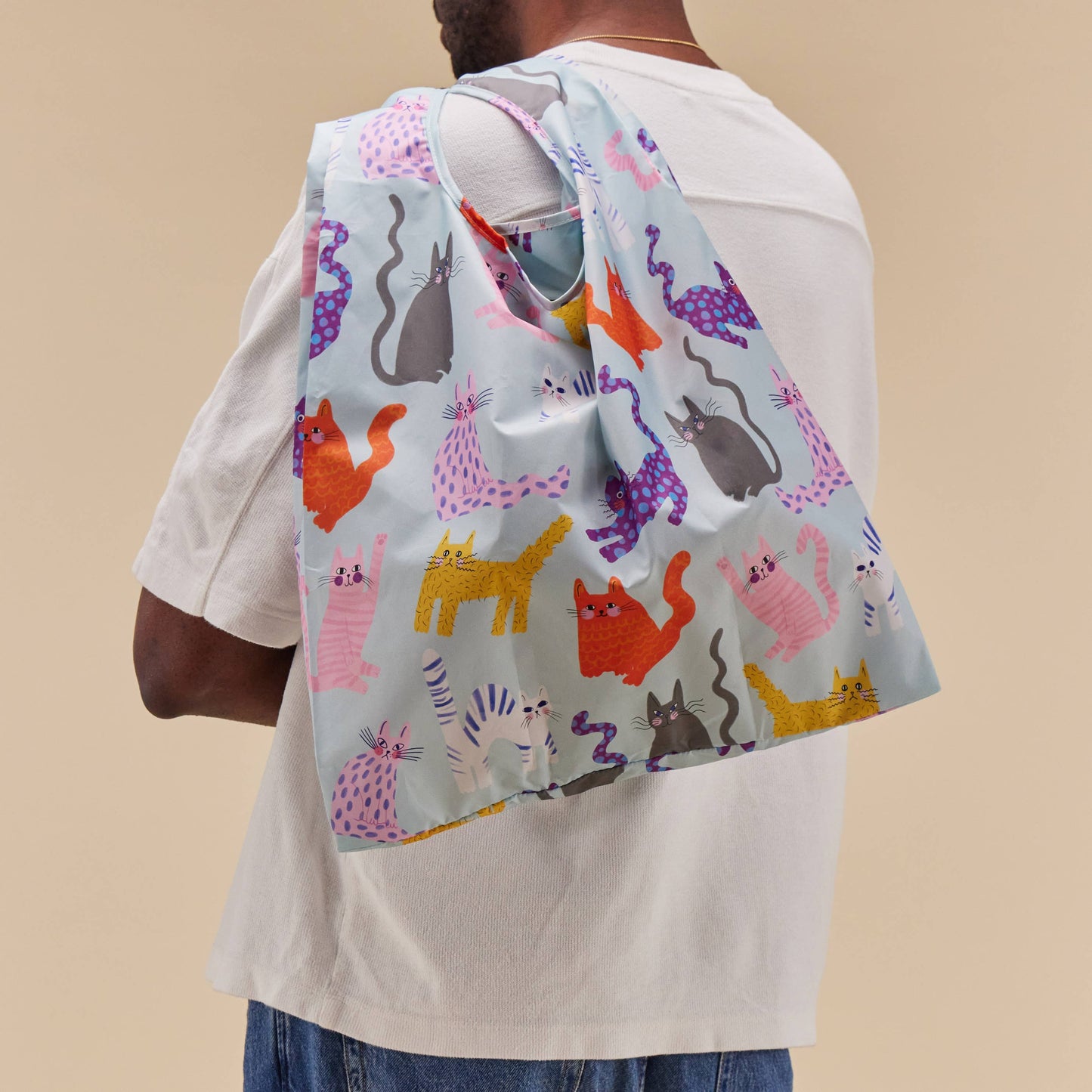 Person wearing a colorful scarf with cat patterns on a beige background