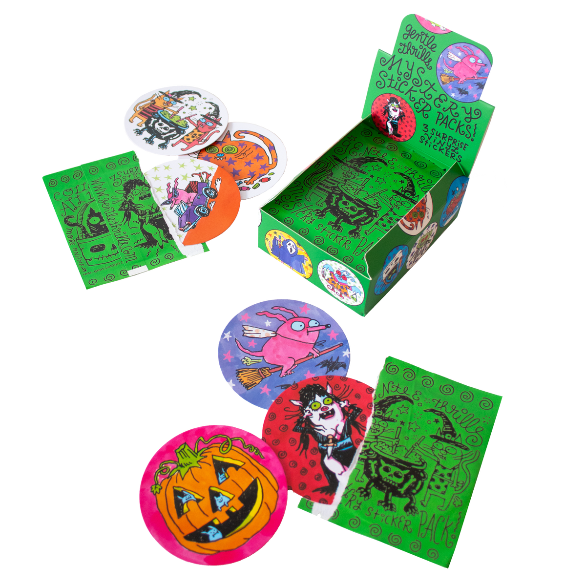 A Halloween-themed paper display box with printed graphics, surrounded by loose round stickers and green rectangular cards on a plain white background.