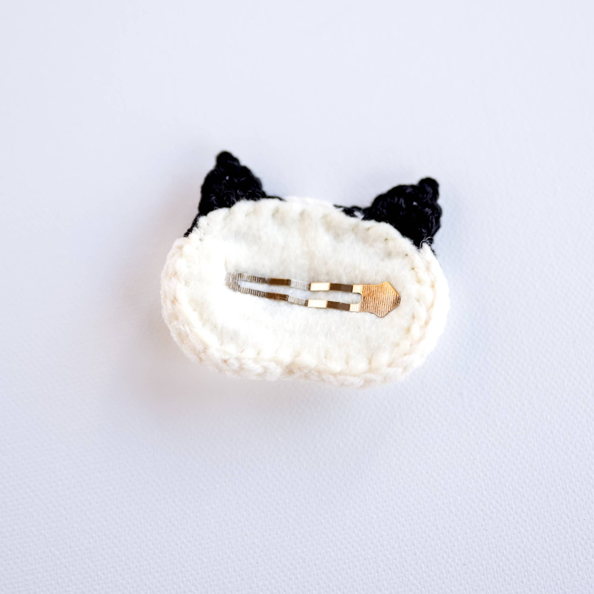 White hair clip with black cat ears on a light gray background