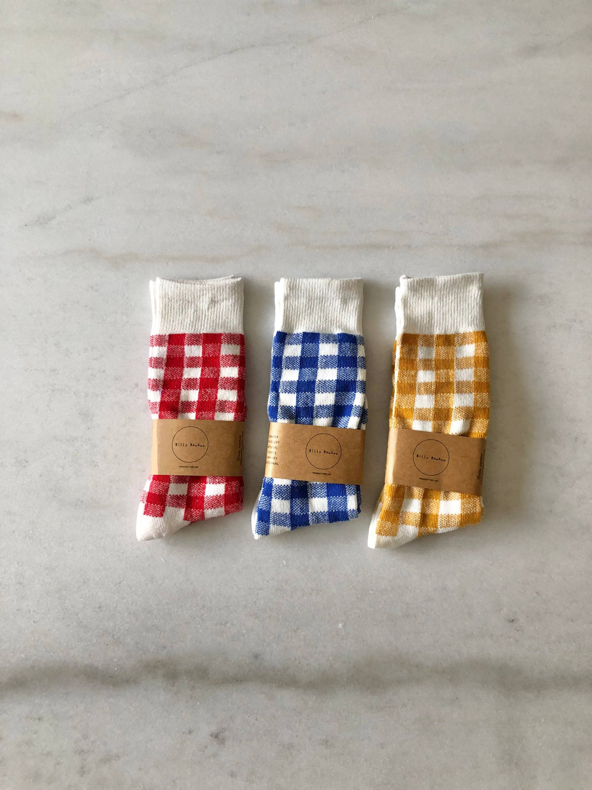Three pairs of checkered socks with branded labels on a gray surface