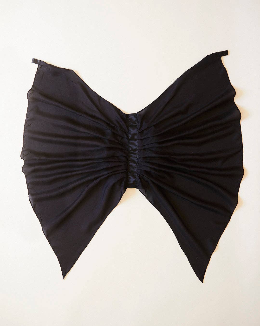 Black bat wings, laid flat on a light cream background.