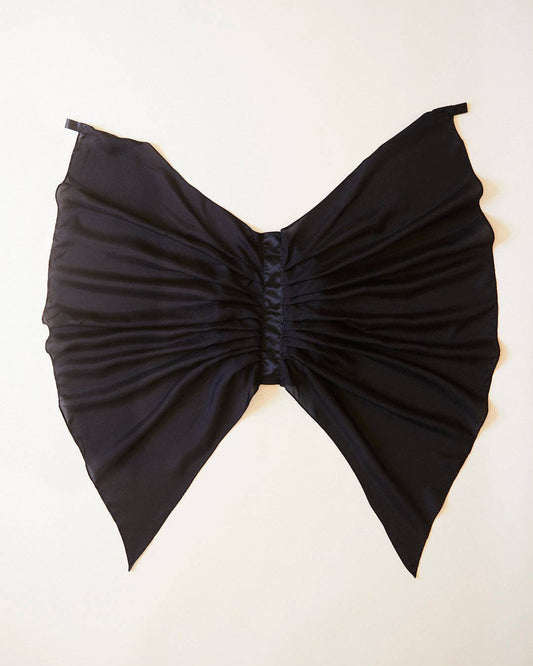 Black bat wings, laid flat on a light cream background.