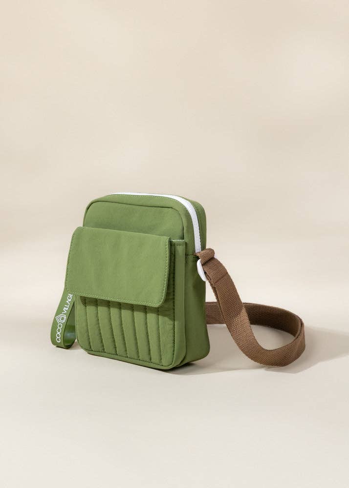 Green crossbody bag with a brown strap on a beige background