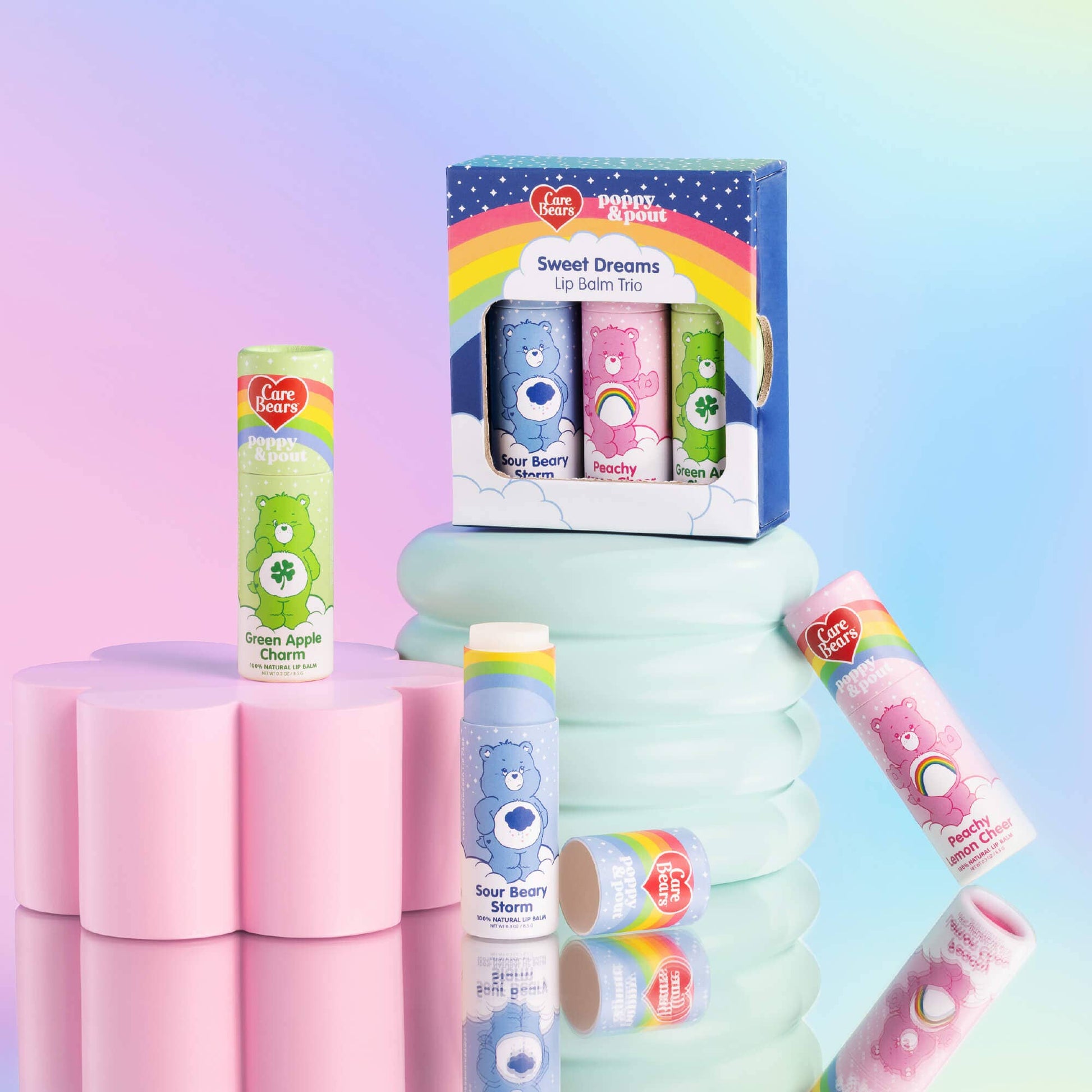 Collection of Care Bears lip balms and a box on a gradient background