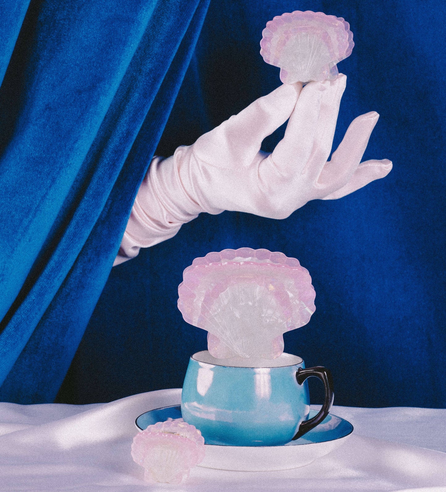 Hand in a white glove holding a pink shell hair clip 