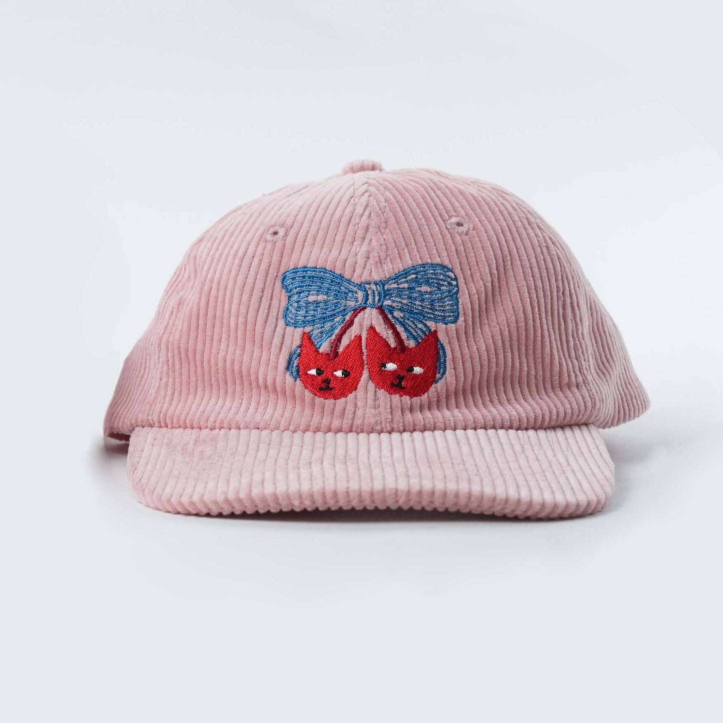 Pink corduroy cap with embroidered design on a white background