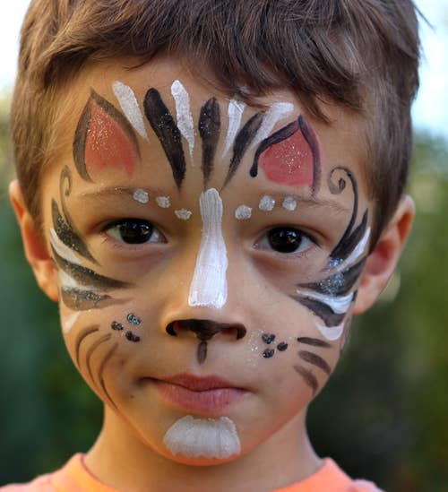 Child with tiger face paint against a blurred natural background