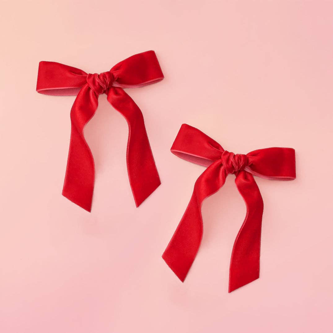 Two red velvet bows on a pink background