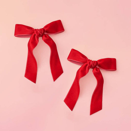 Two red velvet bows on a pink background