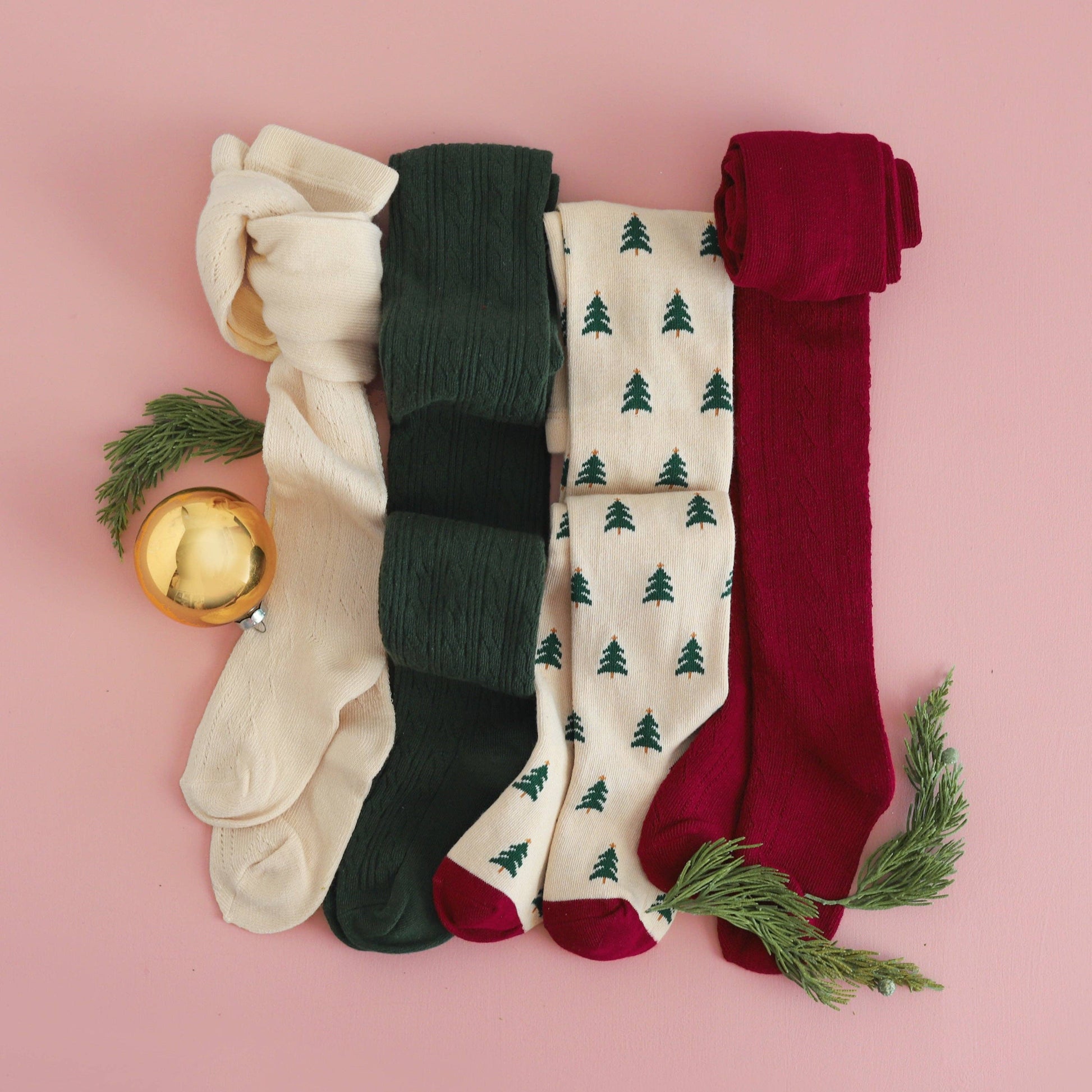 Four pairs of tights in beige, green, white with tree pattern, and red on a pink background.