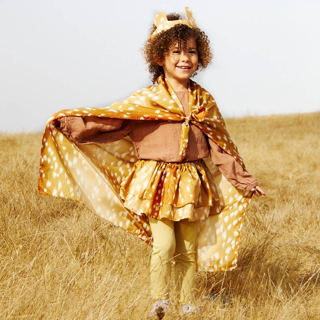 Child in a deer costume standing in a field