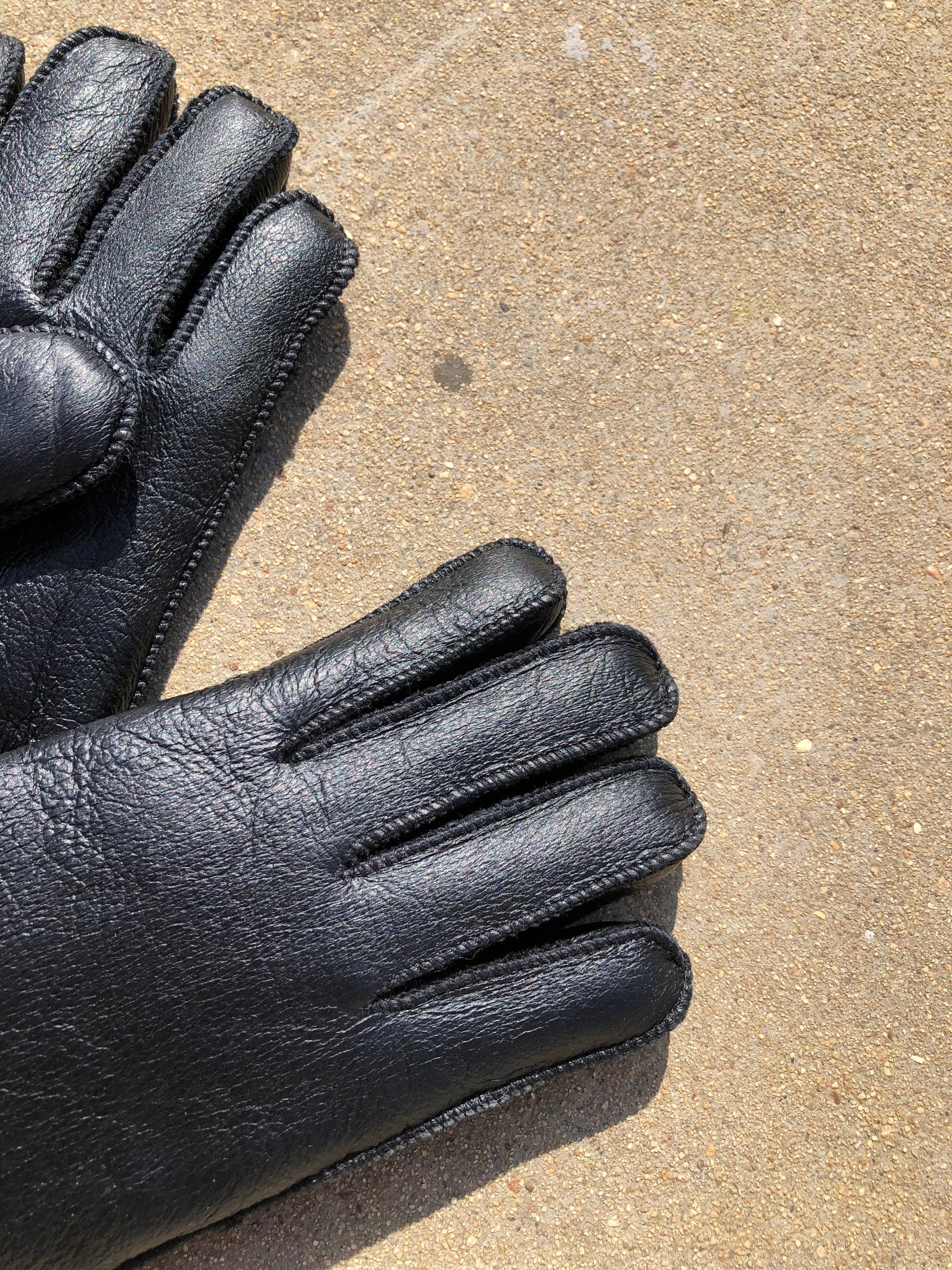 Pair of black leather gloves on a textured surface