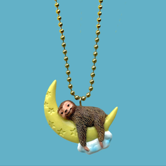 Necklace with sloth on a moon pendant against a blue background