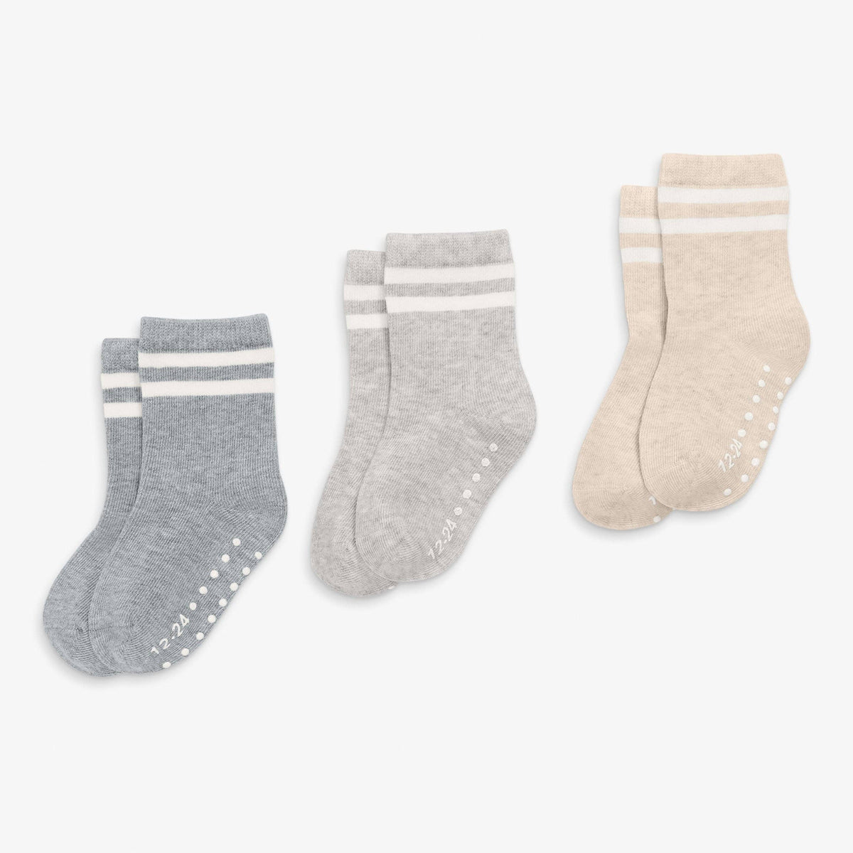 Three pairs of baby socks in gray, white, and beige on a light gray background